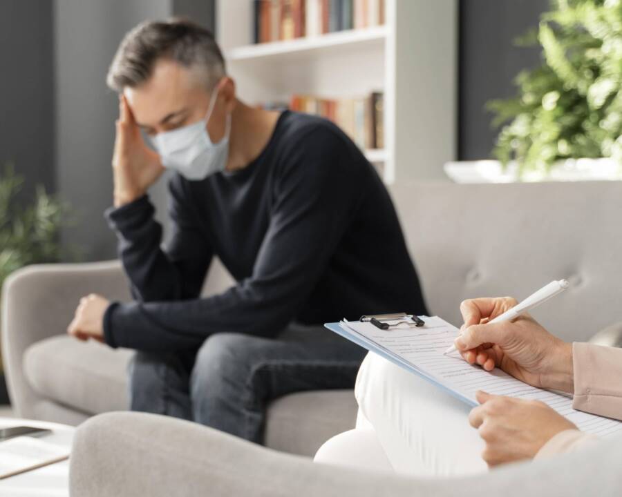 mid-shot-worried-man-with-mask-therapy-office-near-counselor